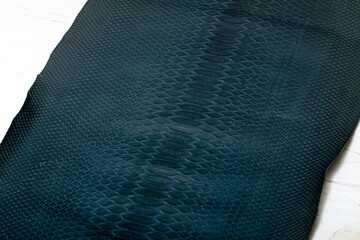 Dark blue dyed genuine natural python leather on the wooden table	
