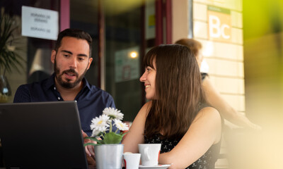 colleague listens to her coworker while he talks at a table in a cafeteria
