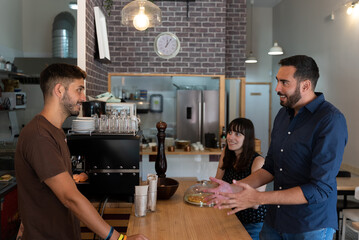 young man and young woman talk to the waiter at the cafeteria bar
