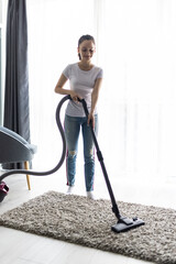 Young pretty woman hoovering carpet at home