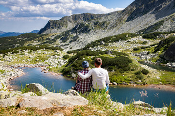 couple sitting on mountain top in amazing summer landscape