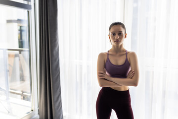 Fit happy woman in sportswear with hands on hips at home in room