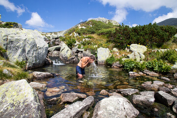 man bathing in crystal clear spring in the mountains