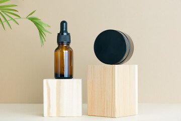 Containers with lotion, serum or essential oil and cream on a wooden podium on a beige background...