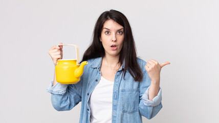 pretty woman looking astonished in disbelief and holding a teapot