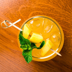 Tropical lemonade with mango and mint in glasses on old wooden background