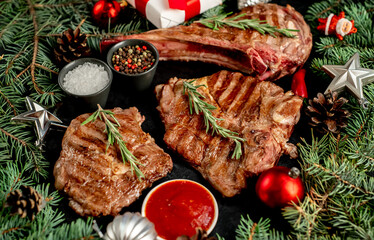 A variety of grilled Christmas beef steaks. Ribeye steak, tomahawk, T-bone, with Christmas tree and...