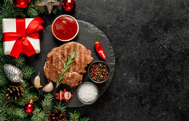 Christmas raw ribeye steak with Christmas tree decorations on stone background with copy space for your text