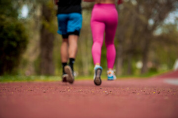 Fototapeta na wymiar Attractive young competitive couple running together outdoors at a park