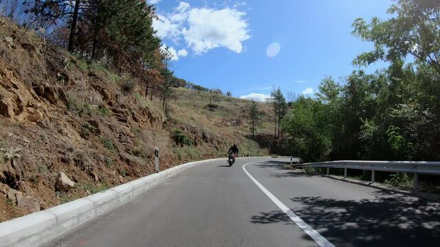 Biker stunt ride biike on mountain rural road and do wheelie on motorcycle