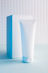 Cosmetic bottle and white cube on a blue background, mock up image