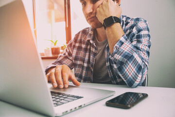 Guy very tired after working online with laptop at home