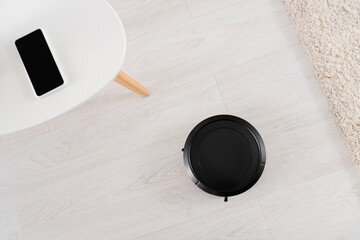 Top view of robotic vacuum cleaner and smartphone at home