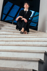 Portrait of a pretty, young businesswoman posing on the stairs in the corporate building.