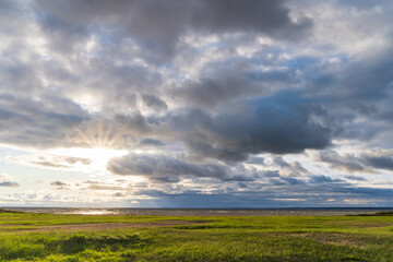 Obraz premium Sun rays through cloudy sky over the North Sea at sunset. Autumn, seascape view background. 