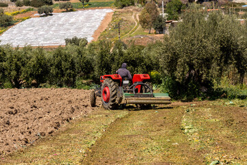 Obraz premium Farmland and tractor working the land on a sunny, spring day