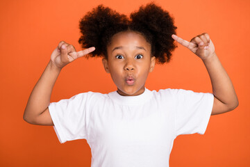 Photo of little impressed girl point hair wear white t-shirt isolated on orange color background