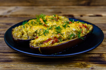 Plate with baked stuffed eggplants on a wooden table