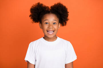 Photo of little funny girl wear white t-shirt isolated on orange color background