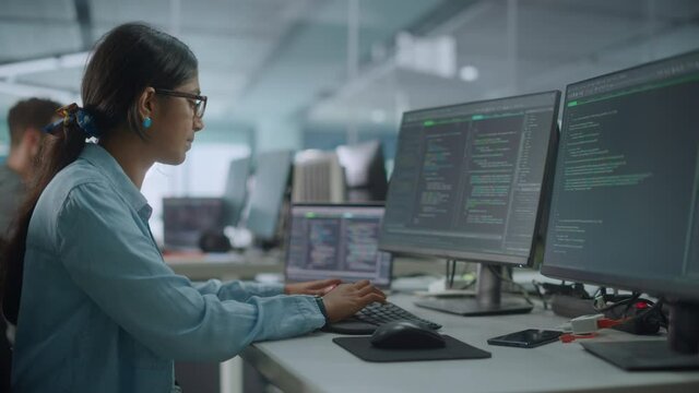 Diverse Office: Indian IT Programmer Working on Desktop Computer. Female Specialist Creating Innovative Software. Engineer Developing App, Program, Video Game. Writing Code in Terminal. Arc Shot