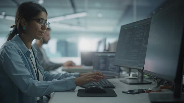 Real Diverse Office: Indian IT Programmer Working on Desktop Computer. Female Specialist Creating Innovative Software. Engineer Developing App, Program, Video Game. Writing Code in Terminal. Arc Shot