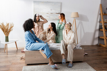 group of happy interracial friends in pajamas during slumber party
