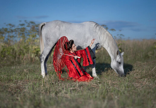 Girl in a red kimono with a white free horse 