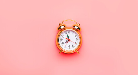 Golden vintage alarm clock on bright pink background in pastel color. Minimal concept, top ciew, negative space