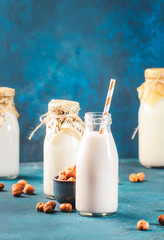 Hazelnut milk on blue table background. Non dairy alternative vegan drink. Negative space