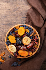 Dried fruits bowl. Healthy food snack: sun dried organic mix of apricots, figs, raisins, dates and other on wooden table, top view