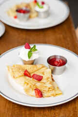 Delicious crepes with fresh strawberries, mint leaves and sour cream espuma. Breakfast at the restaurant. Soft selective focus.