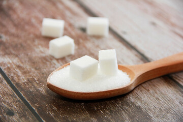 white granulated and sugar pieces in a wooden spoon
