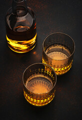 American bourbon whiskey in glasses and bottle, black background with negative space