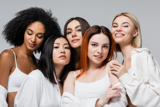 asian and african american models in white shirts posing with cheerful women isolated on grey