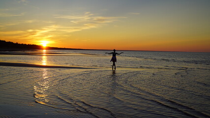 Fototapeta premium silhouette of a woman on the beach at sunset