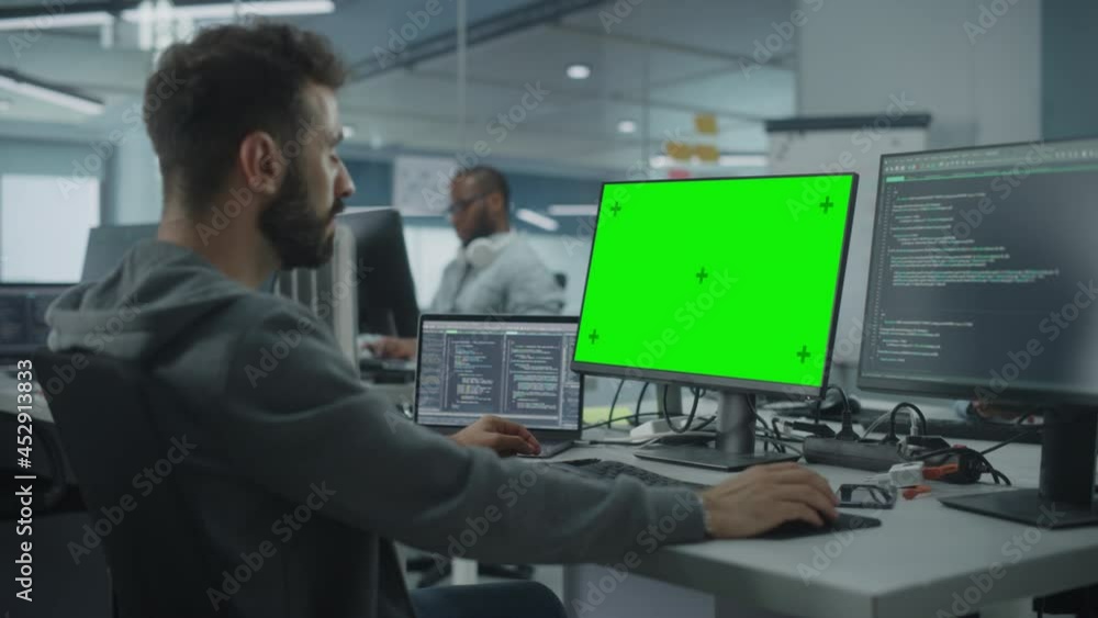 Fototapete Multi-Ethnic Office: White IT Programmer Working on Computer with Green Screen Chroma Key Display. Male Software Engineer Developing App, Program, Video Game. Terminal with Code Language. Static Shot
