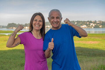 portrait of a young woman and a senior man smiling and doing positive gesture outside on a sunny day