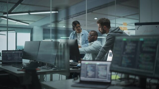 Diverse Multi-Ethnic Team Working in Modern Office: Group of IT Programmers Gather Around Desktop Computer, Talking, Finding Solution. Specialists Create Software. Engineers Develop App, Program