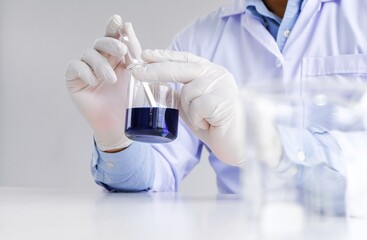 Science innovative Male medical or scientific laboratory researcher performs tests with blue liquid in laboratory. equipment science experiments technology Coronavirus Covid-19 vaccine research