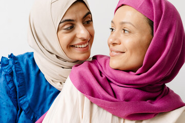 Two middle eastern women in headscarf looking and smiling to each other