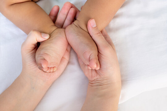hands of a Caucasian mom holding the small legs of her baby black African baby