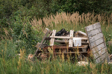 fireplace in meadow, stacked old unnecesary wooden garbage, palettes, planks, boards. Polluted environment