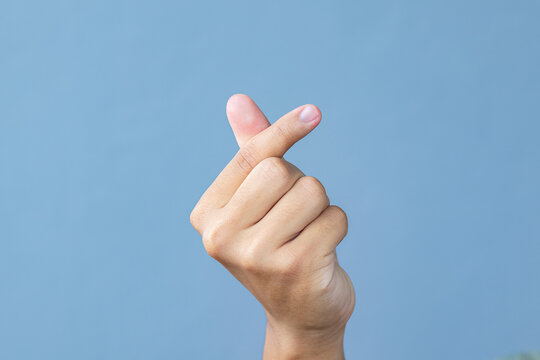 Hand man making miniheart sign on grey background