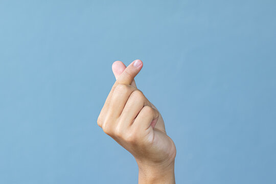 Hand man making miniheart sign on grey background