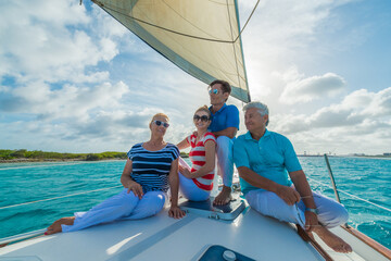Senior and young couples, family, enjoying sailing trip on a luxury summer holiday vacation, sunset and ocean in background, love and romance on a beautiful yacht