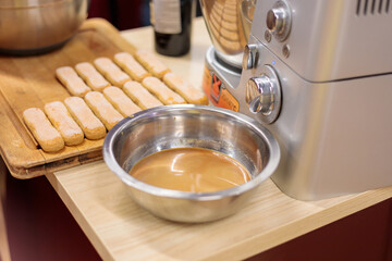 Cookies on the kitchen table with a bowl of tiramisu cream. Savoyards are laid out on a cutting board. Close-up.