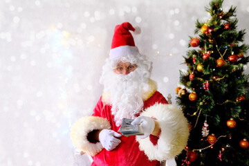 elderly santa claus with a white beard congratulates children and adults, holds banknotes in his hand, gives them, concept of christmas, holiday discounts, shopping, gifts