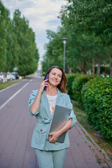 a cheerful girl walking around the city with a laptop