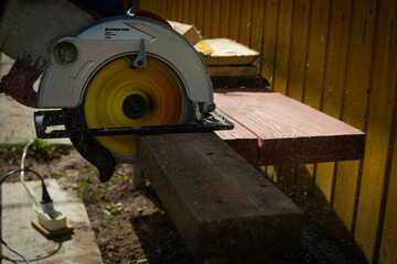 Builder saws a board with a circular saw in the cutting a wooden plank