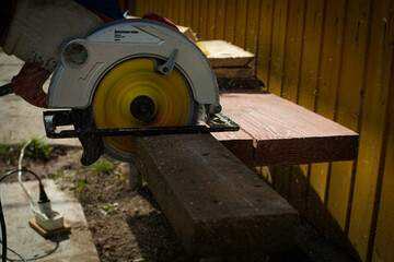 Builder saws a board with a circular saw in the cutting a wooden plank